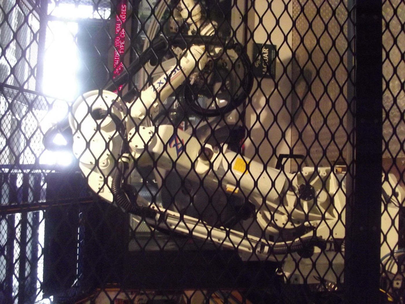 Industrial robot arms welding a car body on an automotive assembly line.