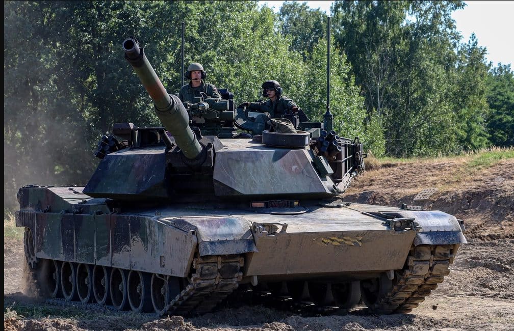 An M1A2 Abrams main battle tank, hull and turret fully visible, during a live training exercise.