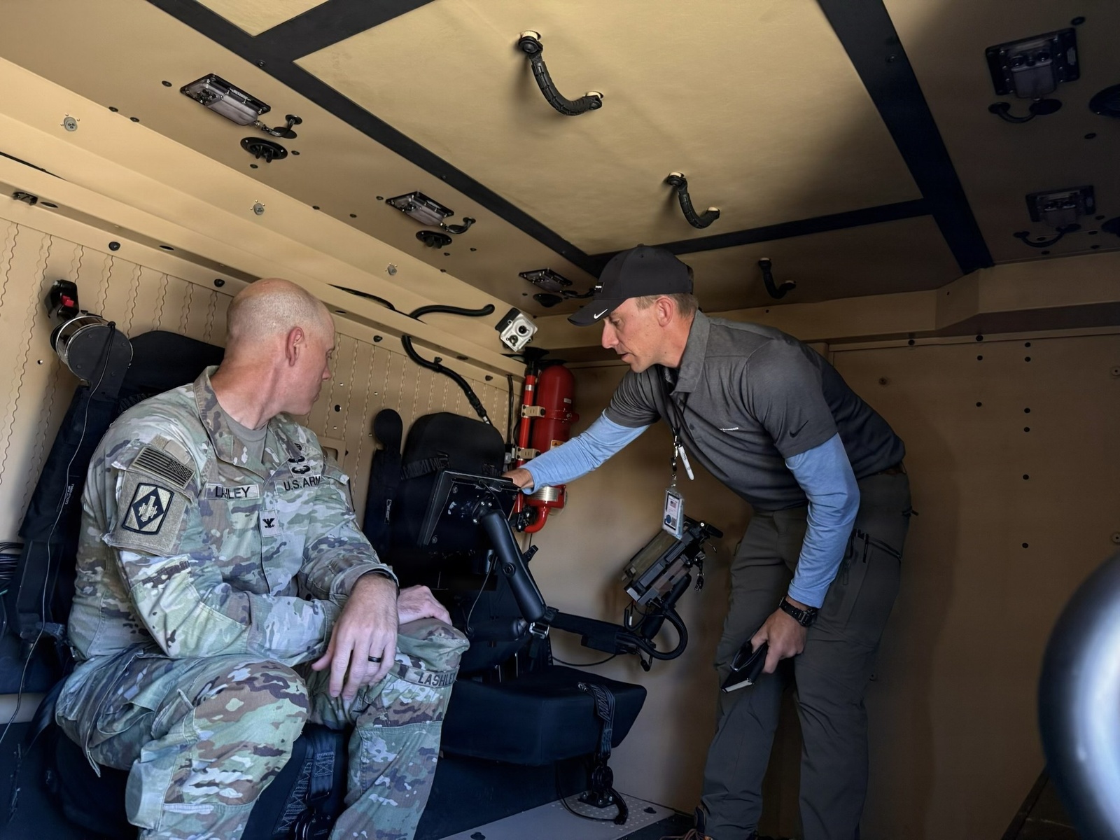U.S. Army Colonel Paul Lashley receiving a briefing on the Joint Unmanned Autonomous System Multi-Payload System Command and Control vehicle from civilian industry partners at a desert training site