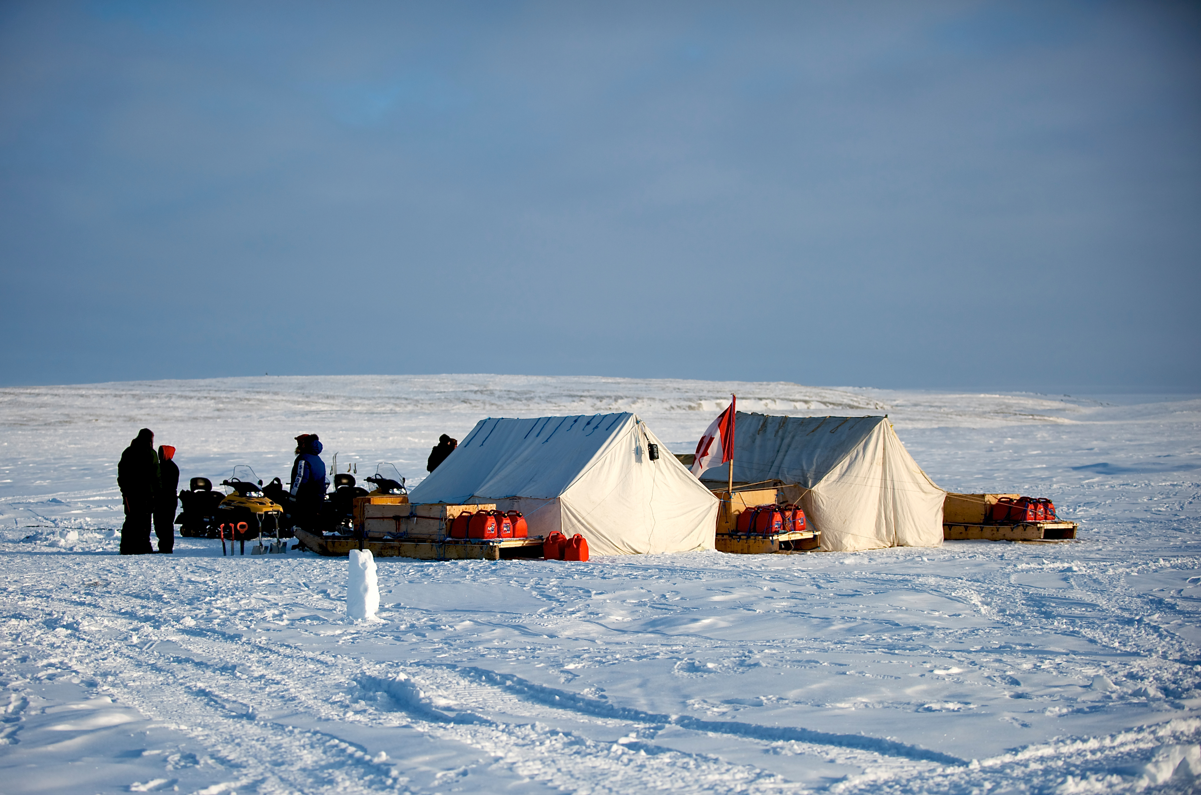 Canadian Rangers gathered at an Arctic training camp in Alert, Nunavut, with snow-covered terrain and support vehicles in the background