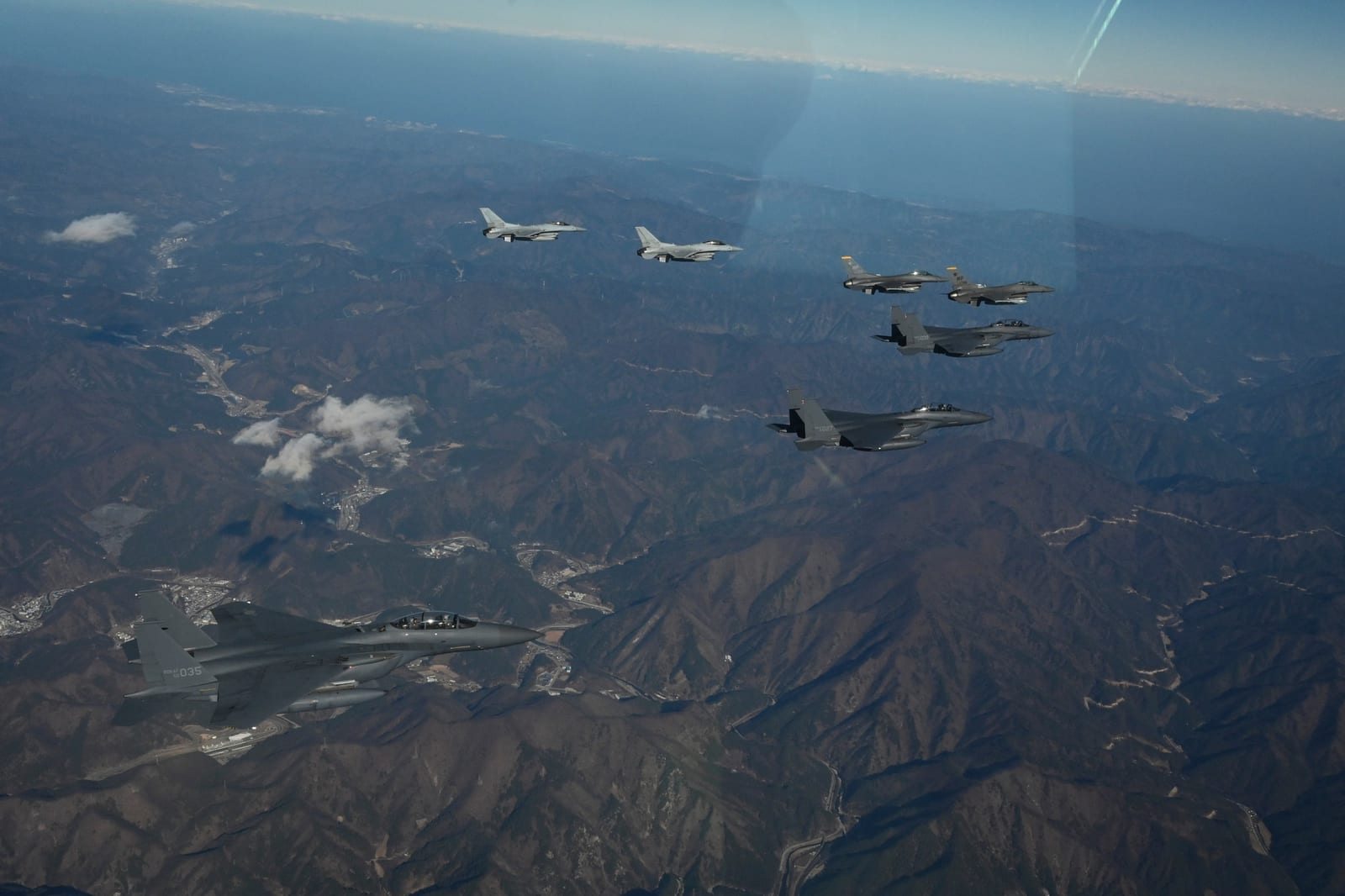 Three Republic of Korea Air Force F-15K Slam Eagle jets and two ROKAF KF-16 Fighting Falcons flying in formation with two U.S. Air Force F-16s over the Korean Peninsula